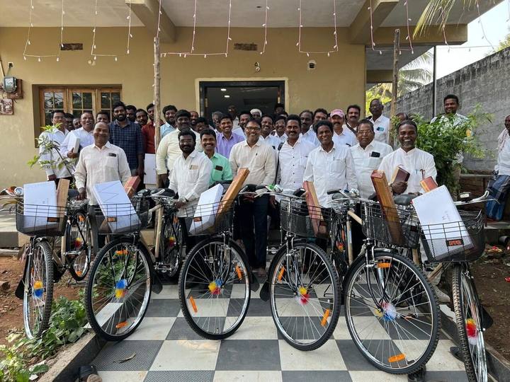 Pastors standing behind a row of new bicycles outside a house