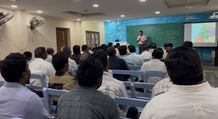 Pastors seated on benches at a training session, seen from the back